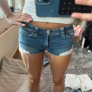 Blå jeansshorts med spetsdetalj - Ett par blåa jeans short med spets design på sidan av shortsen, dom är från hm och är i storlek 158 skriv om ni har några frågor! 💕