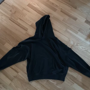 Svart hoodie  - En stilren svart hoodie med stor huva och klassisk magficka. Tröjan har långa ärmar och en relaxed passform, perfekt för chill dagar eller när du vill ha en enkel och snygg look. Materialet känns mjukt och bekvämt mot huden.