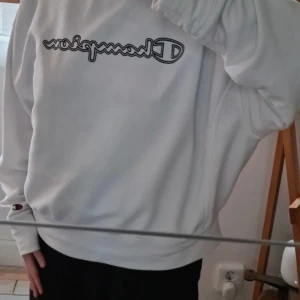 Vit Champion sweatshirt i bomull - Vit sweatshirt från Champion i storlek S. Klassisk modell med rund hals, långa ärmar och broderad logga framtill. Mjuk och skön bomullsmix, perfekt för chill dagar. Diskret Champion-märke även på ärmen.