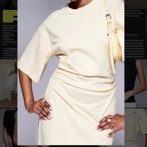 Ljusgul/beige  t-shirtklänning med rynk - Superfräsch ljusgul/beige t-shirtklänning med rynkade detaljer i sidan. Korta ärmar och rund halsringning. Perfekt för en chill och trendig look. Tillverkad i mjuk bomull som känns skön mot huden. Helt ny med prislapp kvar 