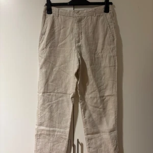 Beiga linnebyxor från Zara - Snygga beiga linnebyxor från Zara med raka ben och klassisk passform. Byxorna har praktiska fickor samt hällor för bälte. Perfekta för en sommardag. Hör av dig vid frågor!