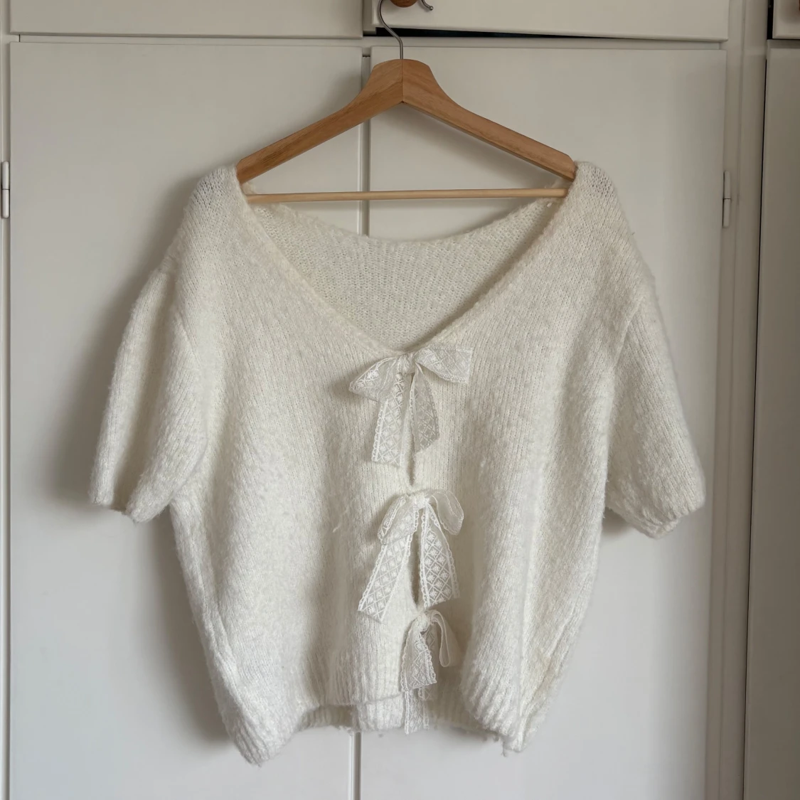 Vit stickad kofta med rosetter JS Millerys