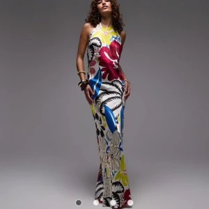 Färgglad långklänning med blommor - Supersnygg långklänning med stora blommor i rött, blått, svart och gult och vitt. Perfekt till bal eller om du är bröllopsgäst osv. Helt oanvänd med lappen kvar! Slutsåld. Passar mig som brukar ha S/M och 38. Men säljer då jag hittade en annan balklänning. 