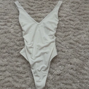 Vit body från Bershka XS - Supersnygg vit body från Bershka i storlek XS. Modellen har djup v-ringning!! den är helt oanvänd då den var för liten för mig💗