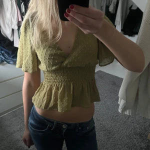 Olivgrön blus med volangdetaljer - Säljer en söt blus med korta ärmar och volangdetaljer. Köpte här på Plick men den kommer inte till användning längre. Står ingen storlek, men jag skulle säga att den är som xs-s. Bra skick!!💚