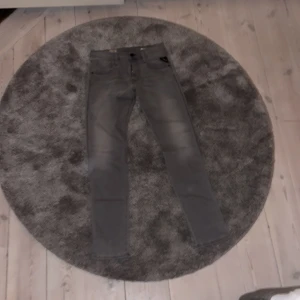 Replay anbass jeans grå slim fit 29/32 - Säljer ett par gråa Replay anbass jeans i slim fit med klassisk femficksdesign. Jeansen har raka ben och snygga slitningar framtill för en cool look. Passar dig som gillar stilrena och moderna jeans med bekväm passform.Nya pris 1800kr jag säljer för 559kr