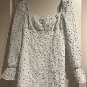 Vit blommig kortklänning med puffärm - Supersöt vit kortklänning med små blå blommor!