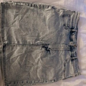 Ljusblå jeanskjol med fickor - Snygg ljusblå jeanskjol med klassiska fickor både fram och bak. Kjolen har bälteshällor och stängs med knapp och dragkedja framtill. Perfekt för dig som gillar en enkel och stilren denimlook.