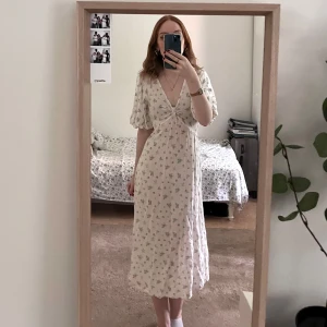 Vit blommig klänning från NA-KD - Jättegullig vit blommig klänning med puffärmar från NA-KD som passar mig som är XS! Köpte för några år sedan till en skolavslutning men säljer för att den inte kommit till användning sedan dess och jag behöver pengar till min student