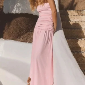 Ljusrosa långklänning från Zara - Superfin ljusrosa långklänning från Zara med draperad överdel och axelbandslös design. Klänningen har en mjuk, flowy passform och är perfekt för sommarens alla tillfällen. Materialet är lätt och svalt, vilket gör den extra bekväm att bära.