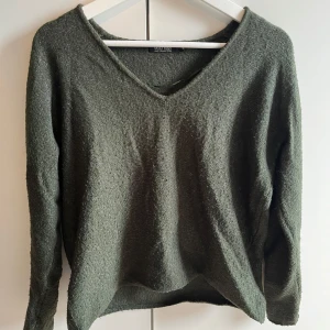 Grön stickad tröja  - Säljer en mysig grön stickad tröja från H&M. Tröjan har en v-ringad hals och långa ärmar, perfekt för kyligare dagar. Enkel och stilren design som passar till det mesta. Perfekt för höst och vinter!