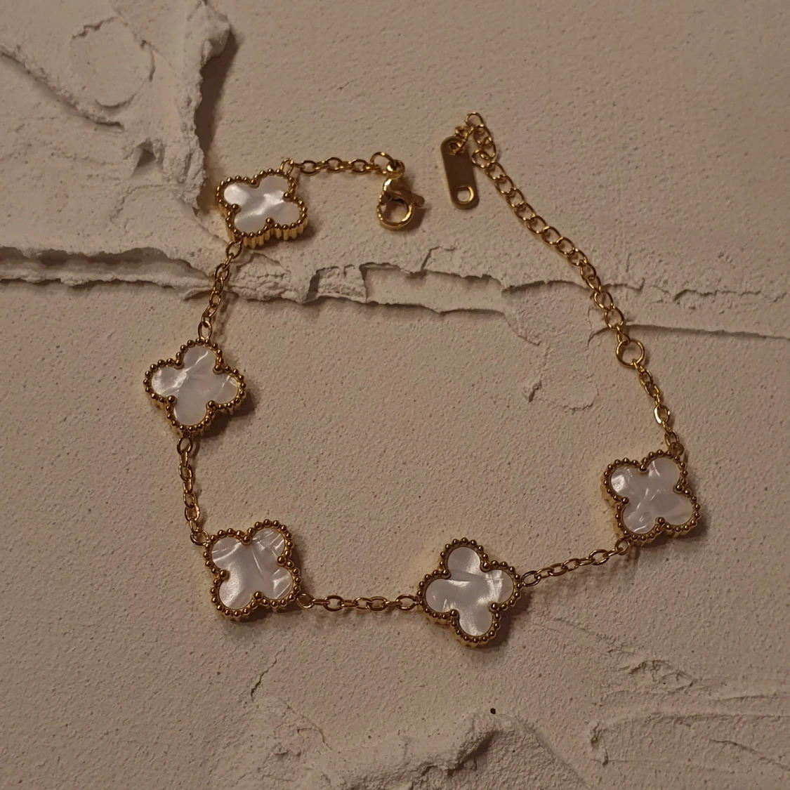 Guldarmband med vita fyrklövers detaljer 
