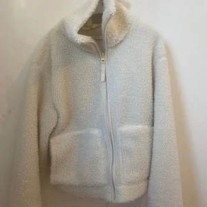 Vit teddyjacka med dragkedja - Mysig vit teddyjacka med dragkedja framtill och hög krage. Slutsåld på hemsidan, jackan är i strl xs och är i nyskick🙌🏼💗