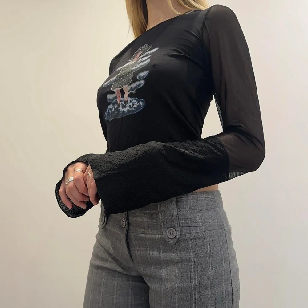 En svart långärmad tröja med tryck, perfekta 90s vibes :) genomskinligt meshtyg på ärmarna och lite utsvängda ärmar. Passar som en S ❤️. T-paidat.