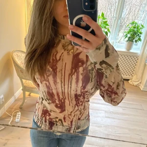 Mönstrad långärmad tröja - Säljer en unik långärmad tröja med ett abstrakt mönster i beige och vinrött. Perfekt för dig som vill sticka ut med en konstnärlig stil. Tröjan har en normal passform och är tillverkad i ett mjukt material, samt lite genomskinlig som ni kan se!💞STORLEK - XL PRIS går att diskutera Skriv om du har frågor 🫶