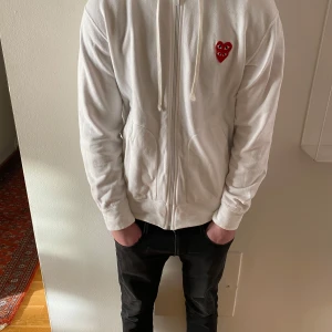 Vit hoodie från Comme des Garçons storlek L/M - Säljer en stilren vit hoodie från Comme des Garçons med det ikoniska röda hjärtat på bröstet. Tröjan är i 10/10 skick. Perfekt för en casual look. OBS Har M i mina andra tröjor 