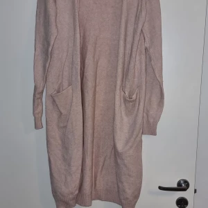Baby rosa lång kardigan, st S - Säljer en lång och mysig baby rosa kardigan med långa ärmar och praktiska fickor framtill. Perfekt för kyliga dagar och att mysa i hemma. Passar till många olika outfits och tillfällen. Mkt fint skick