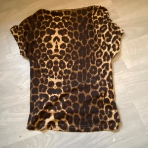 Leopardmönstrad kortärmad topp - Säljer en snygg leopardmönstrad topp med korta ärmar. Toppen är croppad och har en tight passform, perfekt för att ge en trendig look. Den är tillverkad i ett mjukt och bekvämt material.