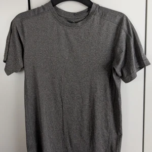 Grå t-shirt från Ronhill - Säljer en stilren grå t-shirt från Ronhill. Perfekt för träning eller en avslappnad dag. T-shirten har en klassisk passform och är kortärmad. Ronhill-loggan syns diskret på framsidan.