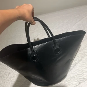 Svart shoppingväska i skinn Nellys kollektion med Bianca  - Snygg och rymlig svart shoppingväska i skinn med två handtag. Perfekt för att bära med sig allt man behöver under dagen. Stilren design som passar till många olika tillfällen. Bianca ingrossos kollektion med Nelly 