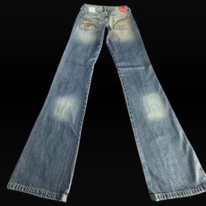 Blå jeans med broderade fickor - Snygga vintage jeans med unika broderade detaljer på bakfickorna🤩 De är lågmidjade och bootcut/flare i modellen. Perfekta jeansen nu inför våren!🌸Nya med prislapp, aldrig använda. Storlek W24/L34. Midjemått:33-34cm Innerbenslängd: 85cm. Vid fler frågor eller funderingar är det bara att skriva!❣️ Pris kan diskuteras!