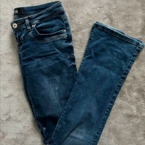 Blå jeans från LTB - Snygga blå jeans från LTB med klassisk femficksdesign och kontrastsömmar. Jeansen har en dragkedja och knapp framtill samt dekorativa sömmar på bakfickorna. Perfekta för en avslappnad stil. BUDA!!!