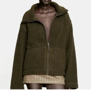 Hm teddyjacka - Mysig olivgrön teddyjacka med dragkedja framtill. Jackan har en avslappnad passform och långa ärmar, perfekt för kyligare dagar. Den har en hög krage som ger extra värme och stil. Den är som ny, endast använd 2 gånger!