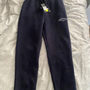 Mörkblå mjukisbyxor från Juicy Couture - Snygga mörkblå mjukisbyxor från Juicy Couture med broderad logga på sidan. Byxorna har en bekväm resårmidja med snörning för perfekt passform. Perfekta för en avslappnad stil. Dock större i storleken så skulle säga mer som M eller S