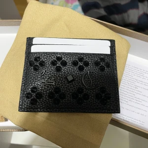 Svart plånbok från Christian Louboutin - Säljer en elegant svart plånbok från Christian Louboutin. Den har ett stilrent mönster med nitar och flera kortfack. Perfekt för att hålla dina kort organiserade med stil. Kommer i originalförpackning.