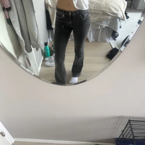 Grå bootcut jeans från Gina tricot - Snygga grå low waist bootcut jeans från Gina tricot. De har en klassisk femficksdesign och är perfekta för en avslappnad stil. Jeansen har en dragkedja och knapp framtill.