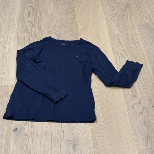 Mörkblå långärmad tröja från Ralph Lauren - Säljer en stilren mörkblå långärmad tröja från Ralph Lauren med det klassiska röda logotypbroderiet på bröstet. 