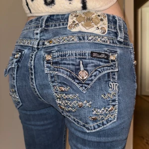 Miss Me jeans  - Snygga blå jeans från Miss Me med broderade detaljer och glittriga stenar på bakfickorna. De har en låg midja och är bootcut. Midjemått rakt över är ca 38 cm, Innerbenslängd 82 cm❤️