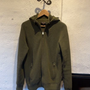 Olivgrön hoodie från Indicode - Säljer en olivgrön cardigan med dragkedja och huva. Jackan har en ribbad struktur och långa ärmar. Perfekt för kyliga dagar! Slutsåld överallt och väldigt eftertraktad. Använd ca 5 gånger. Kan tänka mig byta mot en i storlek M.                                                                     Vid frågor och funderingar hör gärna av er.                                         Mvh Doré.reselll