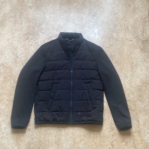 Svart quiltad jacka från Zara - Säljer en svart cardigang jacka från Zara i storlek S. Jackan har dragkedja framtill, ståkrage och två fickor på sidorna.