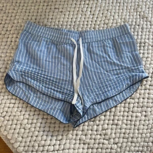 Blåvita randiga pyjamasshorts från H&M - Snygga blåvit randiga pyjamasshorts från H&M i storlek XS. De har elastisk midja med vitt snöre och är tillverkade i ett mjukt bomullsmaterial. 