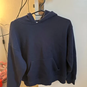 Mörkblå hoodie - En enkel och stilren mörkblå hoodie med huva och magficka. Perfekt för en avslappnad look och passar till det mesta. Mjuk och skön att bära.