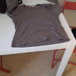 Grå långärmad topp - Säljer en enkel grå långärmad topp med rund halsringning. Perfekt att matcha med jeans eller kjol för en clean look. Mjuk och skön mot huden.