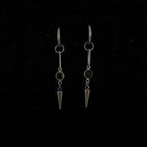 Silverfärgade örhängen med svarta detaljer och konformad hängare - Säljer ett par coola silverfärgade örhängen med svarta runda detaljer och en spetsig konformad hängare. Örhängena har en modern design med ring och avlång länk. Perfekta för att ge din look en edgy touch.