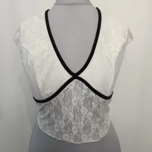 Vit spetstopp - Vit spetstopp med svarta detaljer. Strl S