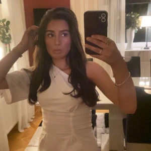 Vit oneshoulder topp - Säljer en stilren vit oneshoulder topp med tight passform. Toppen har en asymmetrisk design med en ärm och en bar axel, vilket ger en trendig look. Perfekt att styla med jeans eller kjol för en snygg outfit.