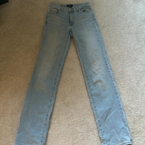 Ljusblå jeansbyxor från Vero Moda - Säljer ett par ljusblå jeansbyxor från Vero Moda med klassisk femficksdesign och raka ben. Jeansen har normal passform och är tillverkade i denim med bälteshällor och dragkedja framtill.