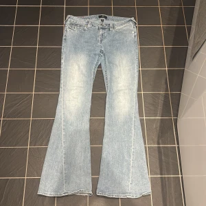 Ljusblå jeans från True Religion  - Säljer ett par ljusblå jeans från True Religion med bootcut passform. Använda ett fåtal gånger. Modell Joey low rise flare. Dessa har dock lite slitningar nedtill pga användning.