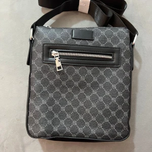 Svart axelväska  - Snygg svart axelväska med  silverfärgad dragkedja framtill. Perfekt för att bära med sig det viktigaste i vardagen.