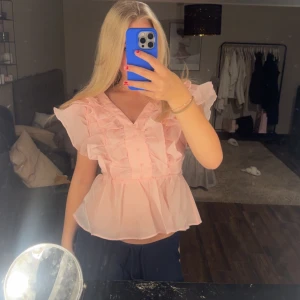Rosa volangblus med knappar - Söt ljusrosa blus med volanger på axlarna och framtill. säljer den pga kommer aldrig till användning 
