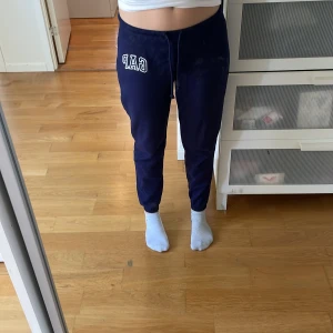 Mörk blå mjukisbyxor från GAP - Säljer ett par mörk blå lågmidjade mjukisbyxor från GAP i storlek XXS. Byxorna är tillverkade av en mjuk blandning av bomull och polyester, med en broderad GAP-logga på sidan. Perfekta för en avslappnad stil. 
