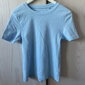 Ljusblå ribbad t-shirt  - Säljer en ljusblå ribbad t-shirt från FSBN Sister. T-shirten har korta ärmar och rund halsringning. Vanligt tight passform storlek S. Aldrig använd 