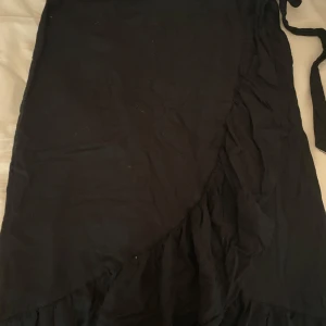 Svart söt omlottklänning  - Säljer en svart omlottklänning från Pimkie. Klänningen har en snygg omlott-design och knytband i midjan. Perfekt för dig som gillar en enkel men stilren look. Tror att storleken är runt xs/s men vet inte helt säkert!