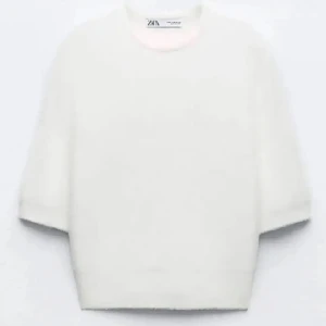 Vit fluffig croppad tröja från Zara - Supermjuk och fluffig vit tröja från Zara med croppad passform och halvlånga ärmar. Perfekt till jeans eller kjol för en enkel men stilren look. Tröjan har en rund halsringning och känns riktigt mysig.