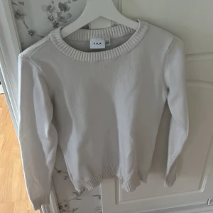 Vit stickad tröja från VILA - Säljer en vit stickad tröja från VILA i storlek XS. Tröjan har rund halsringning och långa ärmar med ribbade muddar vid hals, ärmslut och nederkant.