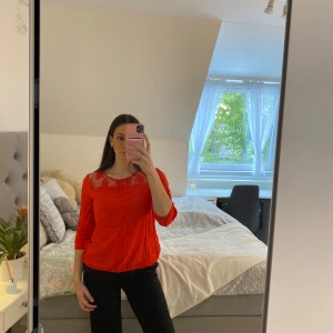 Röd blommig blus från Vero Moda - Säljer en röd blus från Vero Moda med transparent mesh och blommigt mönster. Blusen har trekvartsärm och rund halsringning. Perfekt för dig som vill sticka ut med en färgstark och trendig topp!